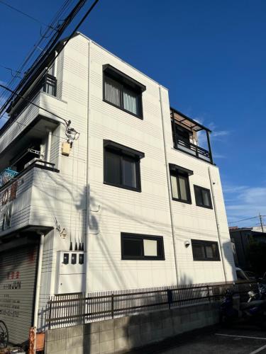 a white building with black windows on the side of it at Shine house warabi in Warabi