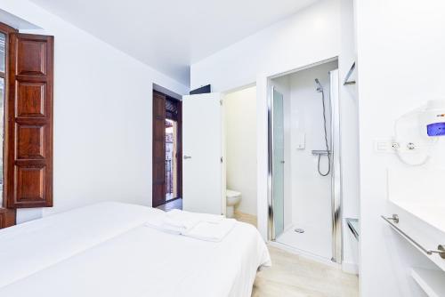 um quarto branco com um chuveiro e uma cama em AMC Granada em Granada
