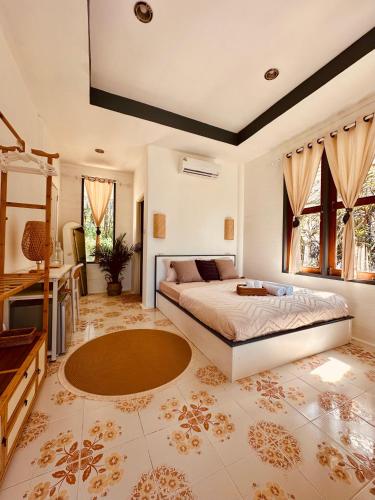 a bedroom with a bed and a desk and windows at Koh Kood Garden House in Ban Lak Uan