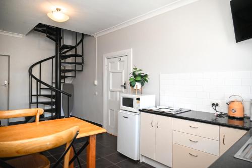 a kitchen with white cabinets and a spiral staircase at Deck Quarters - Mansfield, Victoria in Mansfield