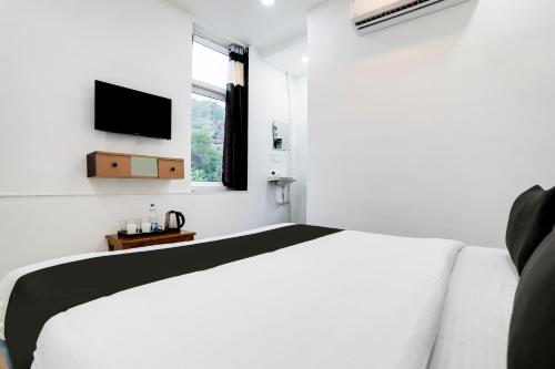 a white bedroom with a bed and a television at Hotel O LAHARI LUXURY ROOMS in Warangal