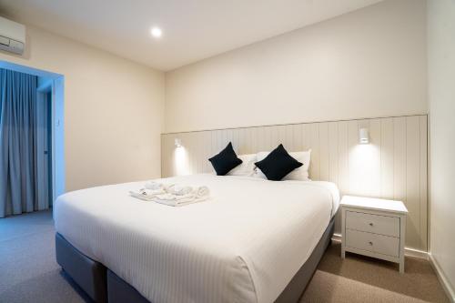 a bedroom with a large white bed with a night stand at The Belmont Hotel in Belmont