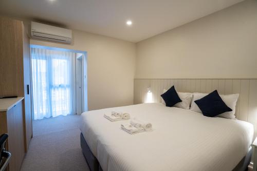 a bedroom with a large white bed with towels on it at The Belmont Hotel in Belmont
