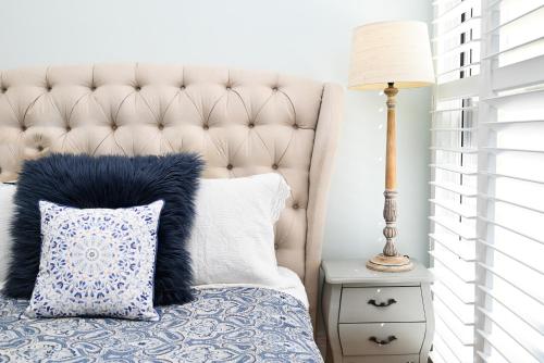 a bed with a blue and white pillow and a lamp at Deck Quarters - Mansfield, Victoria in Mansfield