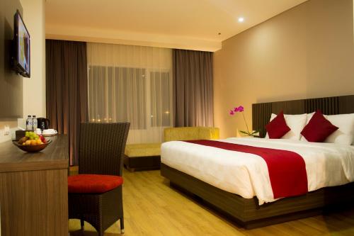 Habitación de hotel con cama, mesa y escritorio. en Merapi Merbabu Hotels Bekasi en Bekasi