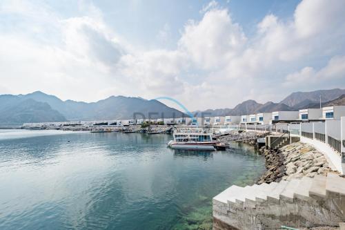 a dock with boats in a body of water at Getaway Offer with Pool, BBQ & Picturesque Views by Deluxe Holiday Homes in Fujairah