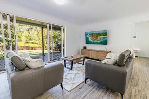 a living room with two couches and a table at Bayview - Three Bedroom, Family & Pet Friendly Coastal Getaway in Agnes Water in Agnes Water