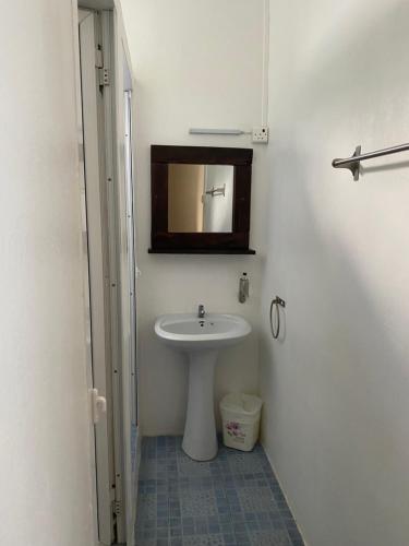 La salle de bains est pourvue d'un lavabo blanc et d'un miroir. dans l'établissement Le Pôle, à Grand Baie