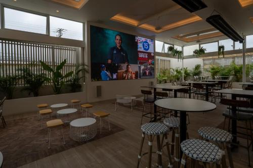 a restaurant with tables and chairs and a large screen at The Belmont Hotel in Belmont