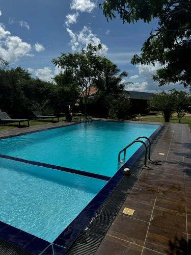 a large blue swimming pool with a metal hand rail at Yala Peace Cottages in Tissamaharama