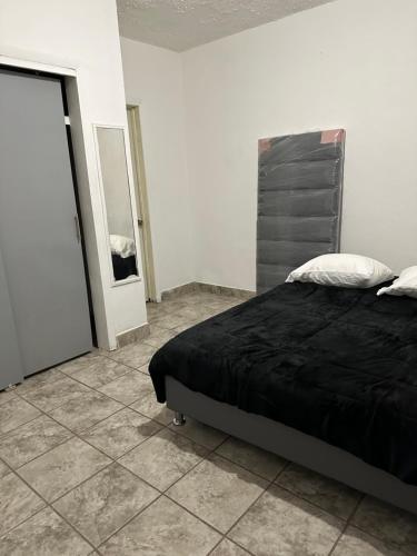 a bedroom with a black bed and a mirror at Departamento independiente en Juárez in Ciudad Juárez