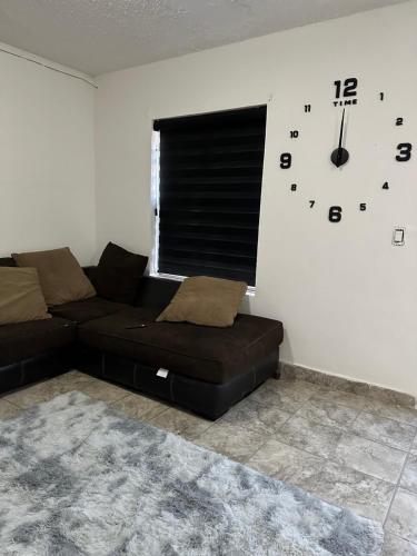a living room with a couch and a clock on the wall at Departamento independiente en Juárez in Ciudad Juárez