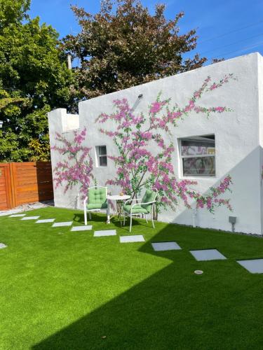 a yard with green grass and a tree with pink flowers at Cozy Casarita Cottage in Miami
