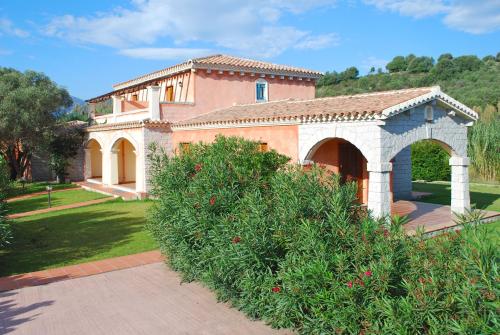 a large house with an arch and a garden at Vecchio Stazzo in San Teodoro