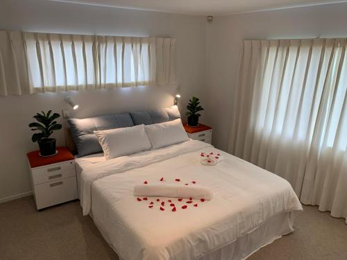 a bedroom with a bed with red rose petals on it at Beautiful room for you in Auckland