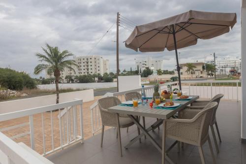 a table and chairs on a balcony with an umbrella at Sun & Sea Seaview Apartment in Protaras