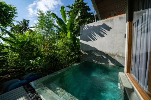 a swimming pool in the side of a house at Langit Pitu Villas in Ketewel