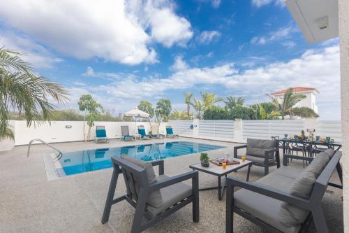 a patio with a pool and chairs and a table at Casa de Nicole in Protaras