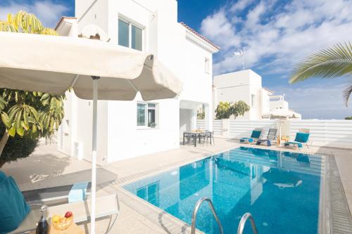 a villa with a swimming pool and an umbrella at Casa de Nicole in Protaras