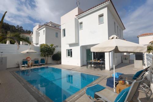 a swimming pool with chairs and an umbrella next to a building at Casa de Nicole in Protaras