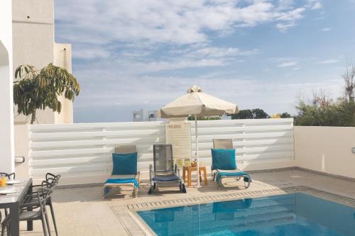 a swimming pool with two chairs and an umbrella at Casa de Nicole in Protaras