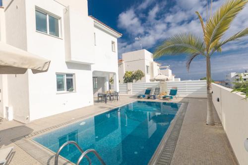 a pool in a villa with a palm tree at Casa de Nicole in Protaras