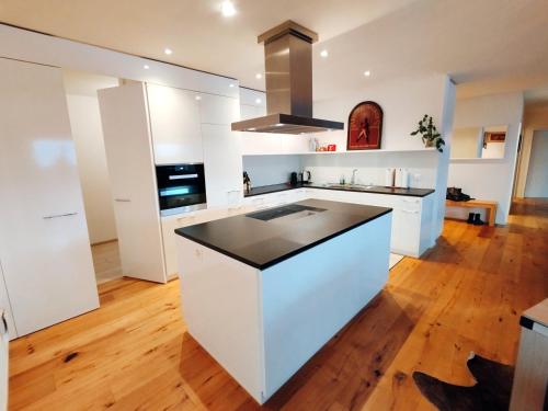 a kitchen with white cabinets and a black counter top at Luxury Escape - Titlis Panorama in Engelberg