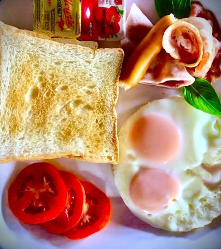 a white plate with eggs and toast and tomatoes at Happy Lagoon Bungalow in Khao Lak