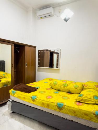 a bedroom with a bed with yellow sheets and a mirror at Homestay Syariah Bayt in Pekalongan