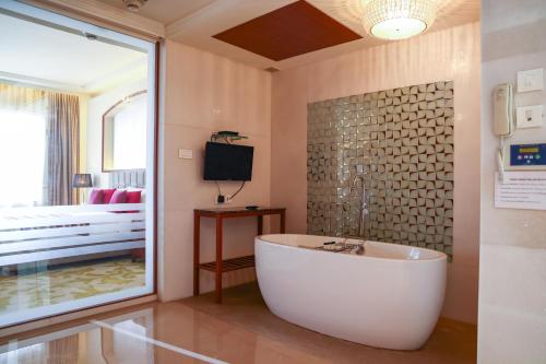 a bathroom with a tub and a bed and a television at Balaji Sarovar Premiere in Solapur