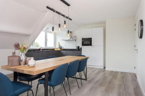 a kitchen and dining room with a wooden table and blue chairs at Appartement Sneekermeer in Sneek