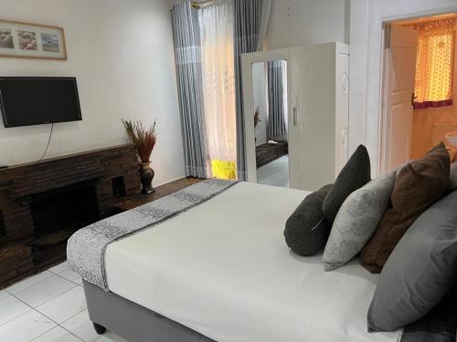 Manshu Guest House في هراري: غرفة نوم بسرير ابيض وموقد