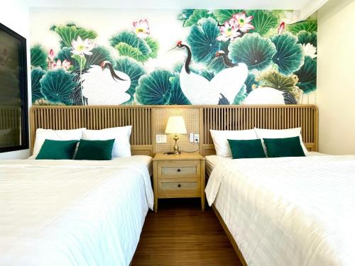 two beds in a room with a mural of swans at FLC Sea Tower Quy Nhon SeaView Condotel in Quy Nhon