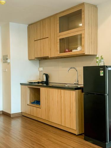 a kitchen with wooden cabinets and a black refrigerator at FLC Sea Tower Quy Nhon SeaView Condotel in Quy Nhon
