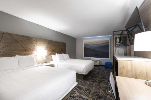 a hotel room with two beds and a flat screen tv at Rodeway Inn & Suites near Outlet Mall - Asheville in Asheville