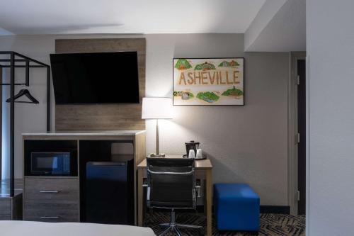 a hotel room with a desk and a television at Rodeway Inn & Suites near Outlet Mall - Asheville in Asheville