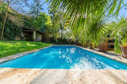 une piscine bleue dans une cour arborée dans l'établissement Château de Cristin du XVIII, authentique et familial - ROSSIconciergerie, à Junas