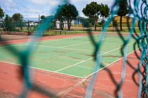 a view of a tennis court through a net at Barefoot Dreams 13A in Jeffreys Bay
