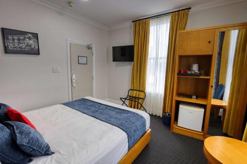 a bedroom with a bed and a table and a window at Ramada by Wyndham, Hamilton City Center in Hamilton