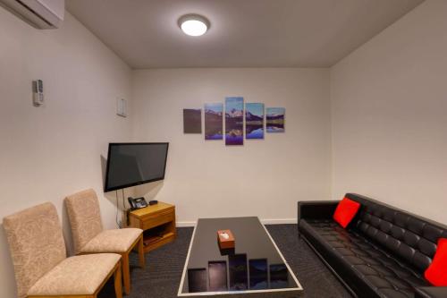 a living room with a couch and a tv at Ramada by Wyndham, Hamilton City Center in Hamilton