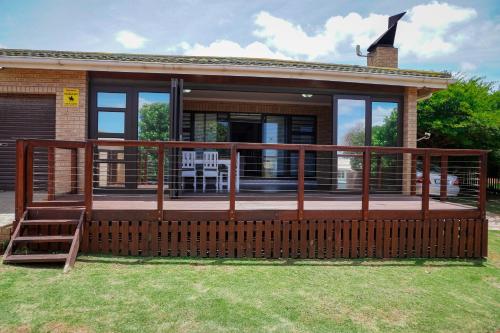 a house with a large wooden deck in the yard at Barefoot Dreams 13A in Jeffreys Bay