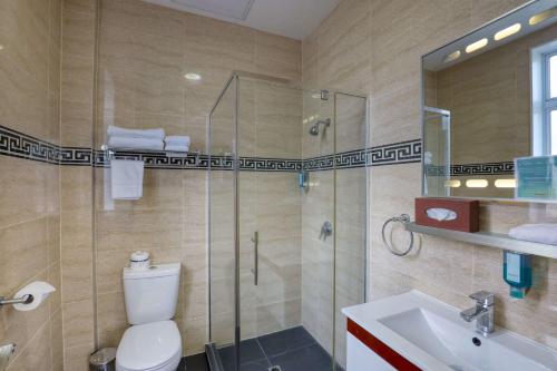 a bathroom with a shower and a toilet and a sink at Ramada by Wyndham, Hamilton City Center in Hamilton