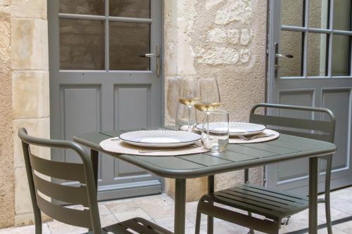 - une table verte avec 2 chaises et des verres à vin dans l'établissement La Cour du Cygne - By PrestiPlace, à Tours