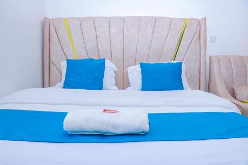 a bed with blue and white pillows on it at Haydenco Suites Signatuture Mall Syokimau in Nairobi