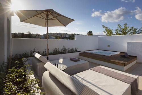 a patio with a couch and an umbrella and a table at Lindian Village All Inclusive Resort Rhodes,Curio Collection in Kiotari