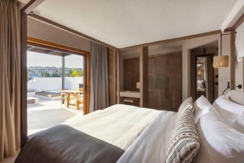 a bedroom with a large bed and a balcony at Lindian Village All Inclusive Resort Rhodes,Curio Collection in Kiotari