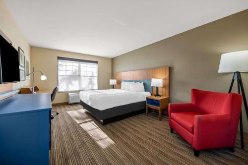 a hotel room with a bed and a red chair at Country Inn & Suites by Radisson, Red Wing, MN in Red Wing