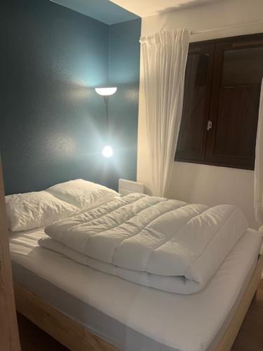 - un lit blanc dans une chambre dotée d'un mur bleu dans l'établissement Appartement lumineux en rez-de- jardin, à Cabourg