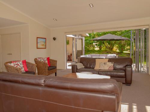 a living room with a couch and chairs and an umbrella at Cooks Getaway - Cooks Beach Holiday Home in Cooks Beach