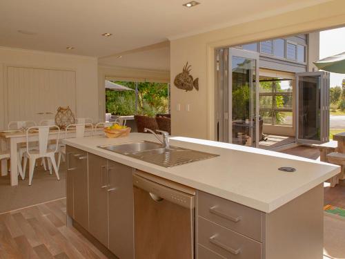 a kitchen with a sink and a dining room with a table at Cooks Getaway - Cooks Beach Holiday Home in Cooks Beach